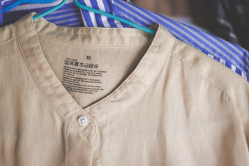 A XL size white cotton hemp shirt hanging on a clothesline with care instruction tag on it.