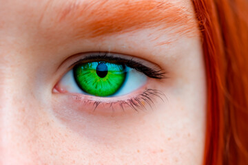 Extreme close cropped portrait of red-haired young teenage girl with green eyes