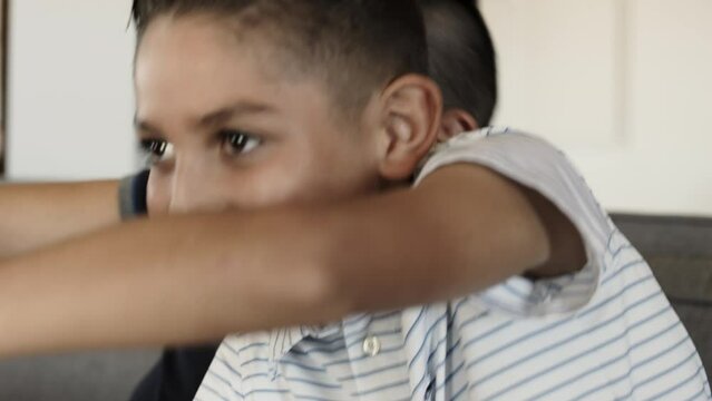 Father and son play video games on a couch in an urban setting