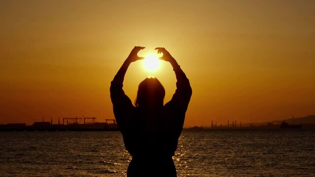 Woman Silhouette Holding Sun in Heart Shape Figure her Hand