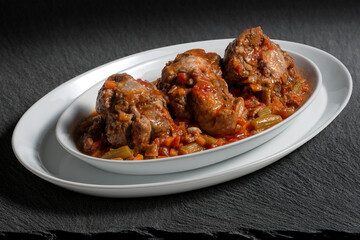 Isolated oval plate with a portion of oxtail stewed vaccinara