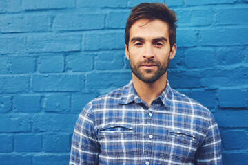 Man, serious in portrait and relax against wall background, casual fashion and cool with blue...