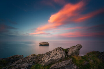 Sunset in Cotonera cove in Islares, Cantabria with a cloudy sky and warm colors and the rock...