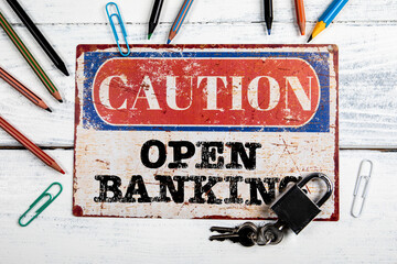 Open Banking. Metal CAOTION plate with text on a white wooden background - 787505318