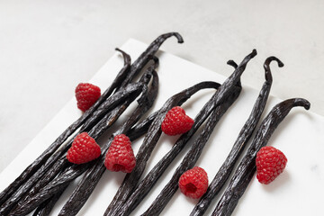 Vanilla beans with raspberries on gray background