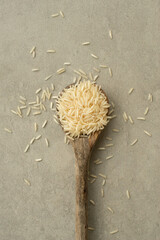 White basmati rice in wooden spoon on gray background