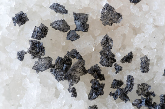 Heap of small stones of black salt on top of white salt, used in cooking seasonings