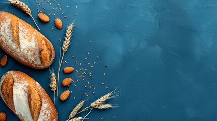 Freshly baked bread loaves with almonds and wheat ears on a blue textured background. Bakery and natural ingredients concept with copy space.
