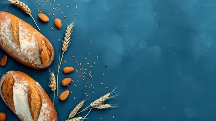 Photo sur Plexiglas Pain Freshly baked bread loaves with almonds and wheat ears on a blue textured background. Bakery and natural ingredients concept with copy space.