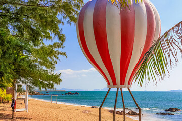 View of the shore of the South China Sea with a sandy beach, palm trees and a hot air balloon, China