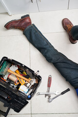 Man, plumbing and tools in box on floor with maintenance for construction, inspection or repair in...