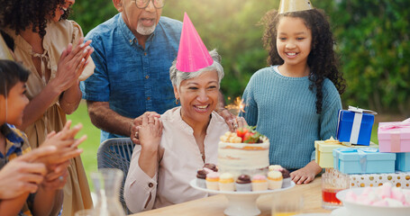 Senior woman, birthday cake and family in garden with applause, celebration and happy together for party. Man, women and children in grandparents backyard with present, dessert and love in summer