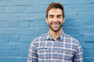 Man, happy in portrait and relax against wall background, casual fashion and positivity with blue...