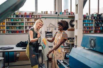 Interracial printing shop female workers doing quality control of product