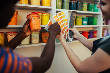 Interracial graphic workers' hands choosing paint buckets for printing