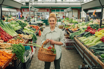 Portrait of happy customer with basket full of groceries at marketplace