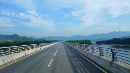 A long road bridge over the river with views of the mountains in the distance. Asphalt highway.