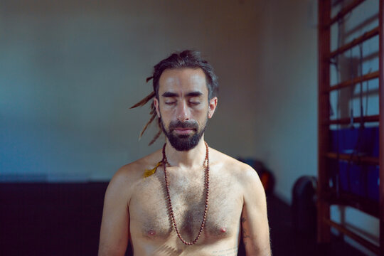 head shot portrait shirtless latin American yogui sitting practicing Hata yoga meditating eyes closed  indoors	