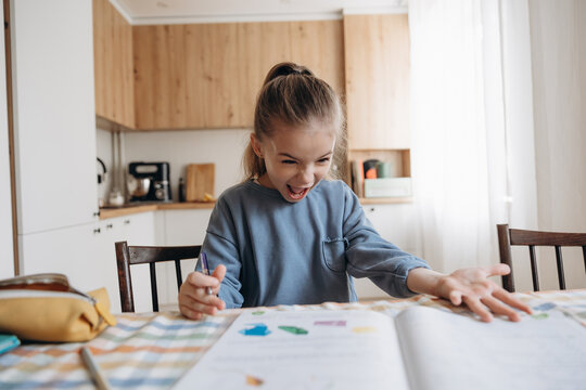 emotionally excited and angry first grader doing homework at home at the kitchen table