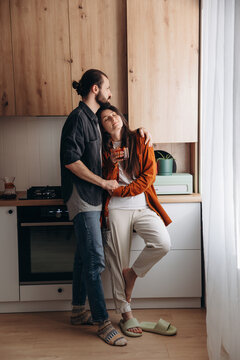 a young happy couple, husband and wife, are peacefully hugging in their kitchen