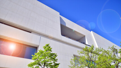 Modern white concrete building walls against blue sky. Eco architecture. Green trees and concrete...