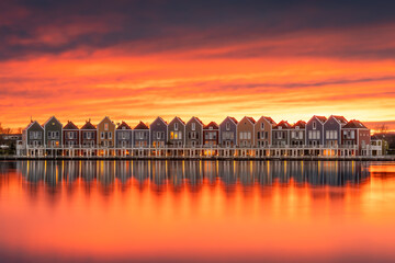 Row of houses near water at sunset with amber sky and afterglow