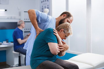 Caucasian senior woman receives checkup from physiotherapist. Patient, recovering from back pain,...