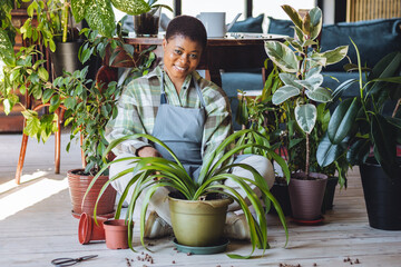 Concept of mental health, hobbies, do favourite things on leisure time. African American woman doing home gardening, repotting plants, taking care about flowers. Domestic life, interior design