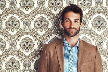 Portrait, serious and man in suit on a wallpaper background isolated in studio for vintage fashion. Face, style and confident person in clothes, blazer or retro pattern of classy model in Switzerland