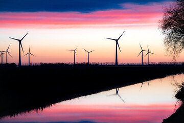 Windmills lining a river at sunset, enhancing the natural landscape
