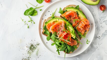 Avocado, salmon, and fresh greens toast on white plate, top view for a stylish presentation