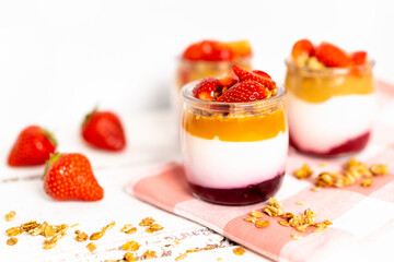 Fruit yogurt berry with muesli and fresh strawberries, on a white wooden background