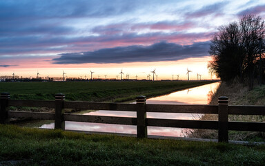River enclosed by wooden fence with sunset sky and clouds in the background