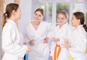 Group of young women are talking after successful and tedious aikido workout. Coach and students...