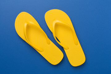 Bright yellow flip-flops on color background, top view. Summer concept