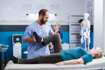 Physiotherapist stretching leg muscle to relieve pressure for recovery of senior woman. Doctor...