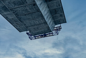 concrete bridge under construction, seen from below with the roadway suspended in the air against a blue skyCrown Princess Marys bridge hangs in the air connecting to the next pylon