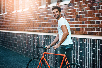 Happy, bicycle and portrait of man by brick wall in city for sightseeing on vacation or adventure....