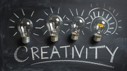 Hand drawn chalk lettering CREATIVITY on blackboard next to glowing light bulbs symbolizing idea generation and brainstorming