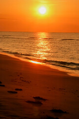 amanecer dorado de verano en playa con huellas en la arena