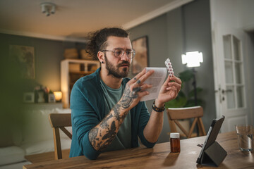 One adult man read recipe for medicament on tablet at living room at home - obrazy, fototapety, plakaty