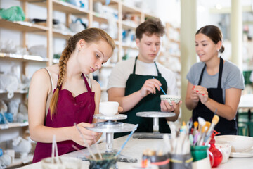 Teenagers are interested in making dishes from clay in a pottery workshop