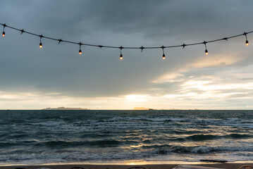 Sunset Seascape with Festive String Lights Over Beach
