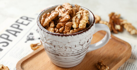 Cup of tasty walnuts on beige background