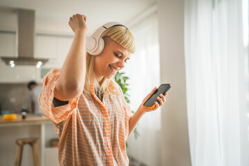 Young woman with headphones listen music on mobile phone happy