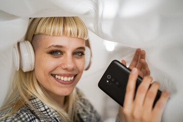 Young woman with headphones listen music on mobile phone happy - obrazy, fototapety, plakaty
