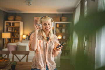 Young woman with headphones listen music on mobile phone happy