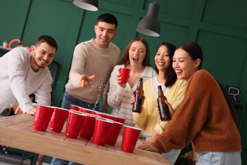 Group of young friends playing beer pong at party