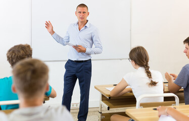 Fototapeta na wymiar Portrait of male teacher lecturing to teenage students at auditorium