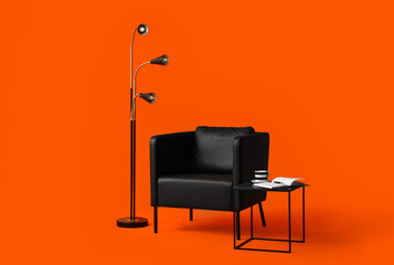 Modern black leather armchair, lamp and coffee table on orange background